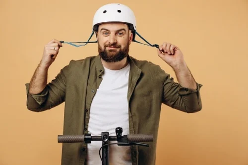 Man mit Helm auf einem E-Scooter
